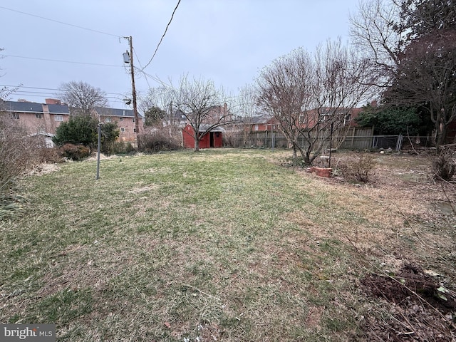 view of yard featuring a storage unit, an outdoor structure, and fence