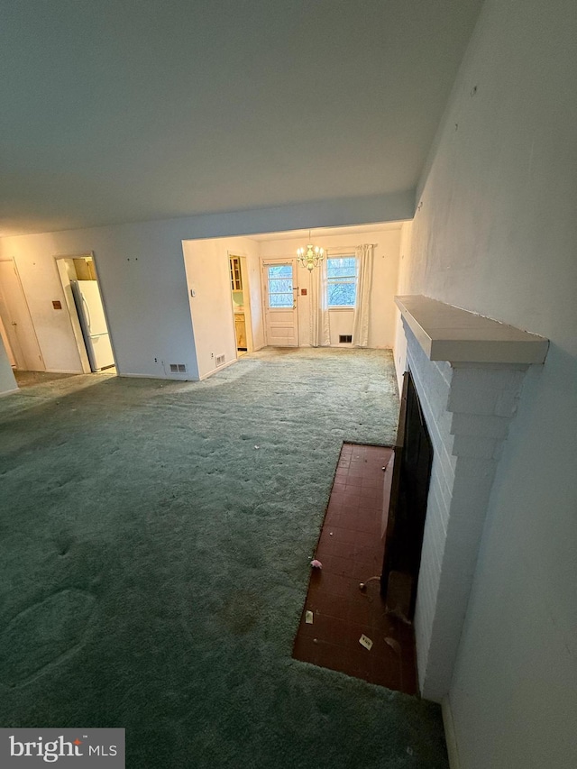 unfurnished living room with a notable chandelier, visible vents, and carpet floors