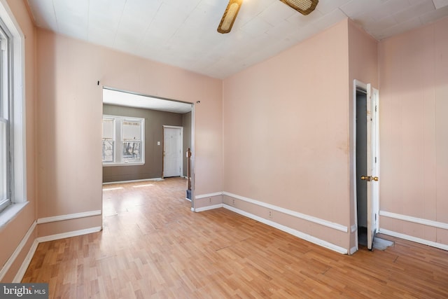 empty room featuring ceiling fan, baseboards, and wood finished floors