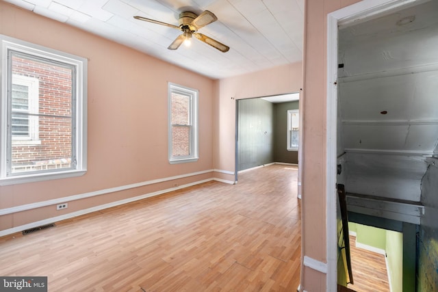 interior space featuring baseboards, a ceiling fan, visible vents, and light wood-type flooring