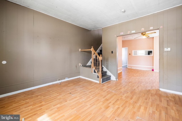 unfurnished living room featuring baseboards, a ceiling fan, wood finished floors, and stairs