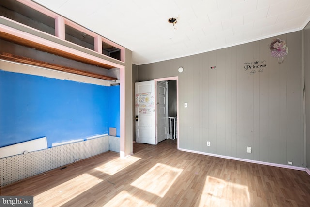 unfurnished bedroom with baseboards, wood finished floors, and crown molding