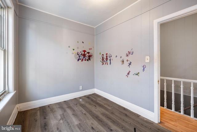 empty room with baseboards, wood finished floors, and crown molding