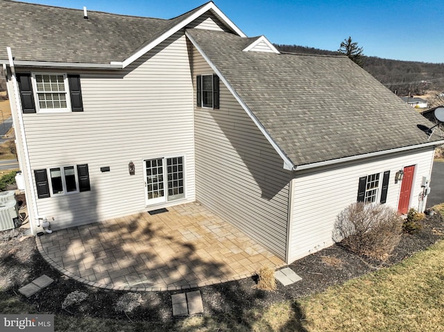 rear view of property with a patio and a shingled roof