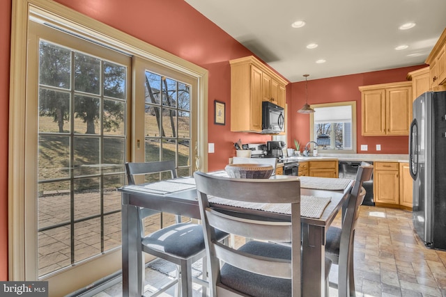 kitchen featuring recessed lighting, black appliances, light countertops, stone finish flooring, and pendant lighting