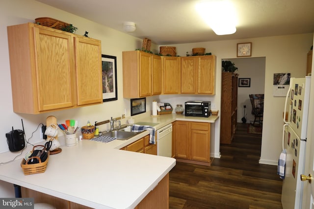 kitchen featuring dark wood-type flooring, a sink, white appliances, a peninsula, and light countertops