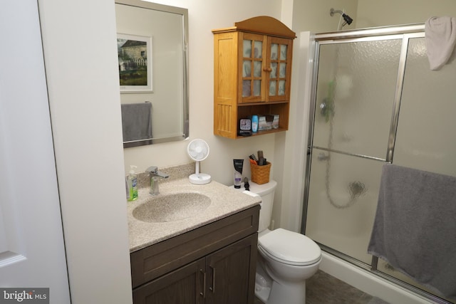 bathroom with toilet, a stall shower, and vanity