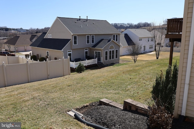 back of house featuring a residential view, a wooden deck, a yard, and fence