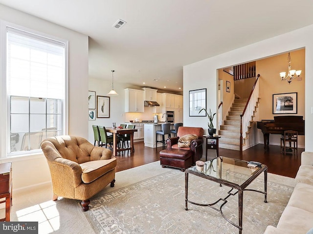 living area with stairs, plenty of natural light, visible vents, and a chandelier