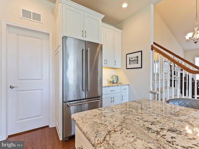 kitchen with visible vents, a notable chandelier, high quality fridge, white cabinets, and light stone countertops