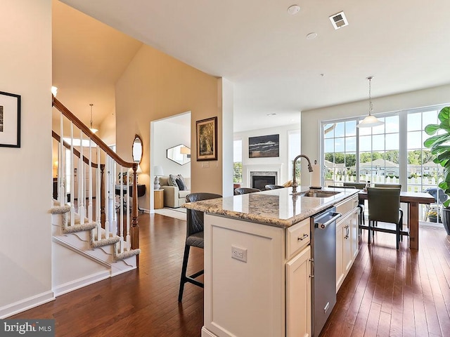 kitchen with visible vents, dark wood finished floors, a fireplace, stainless steel dishwasher, and a sink