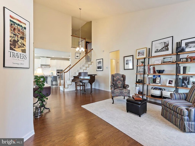 living area with an inviting chandelier, stairs, baseboards, and wood finished floors