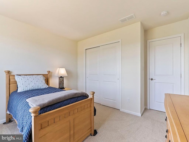 bedroom with a closet, visible vents, light colored carpet, and baseboards