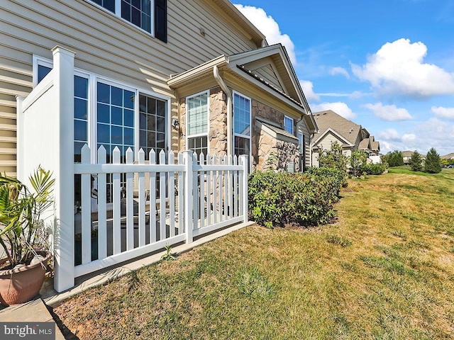 view of side of home featuring stone siding and a lawn