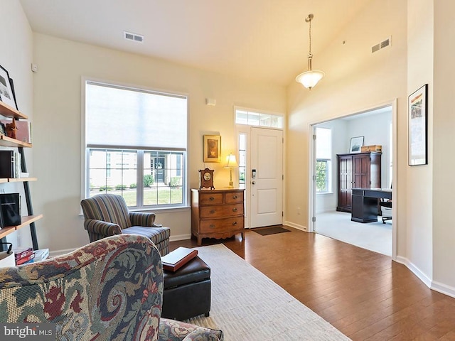 living area with wood finished floors, a healthy amount of sunlight, visible vents, and baseboards