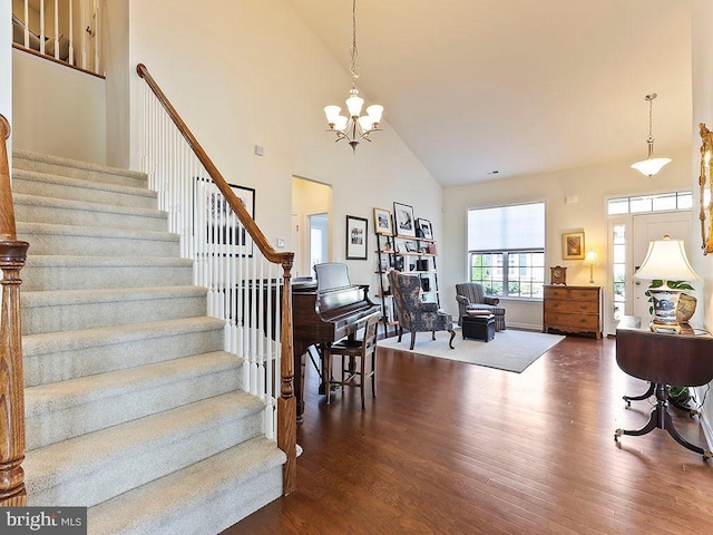 stairs featuring a chandelier, a high ceiling, and wood finished floors