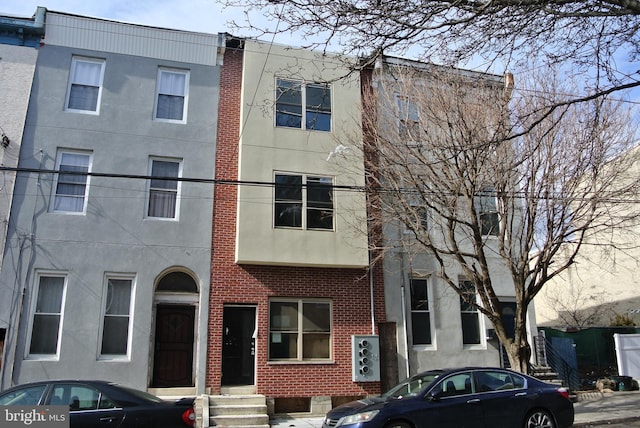 townhome / multi-family property with brick siding, stucco siding, and a chimney