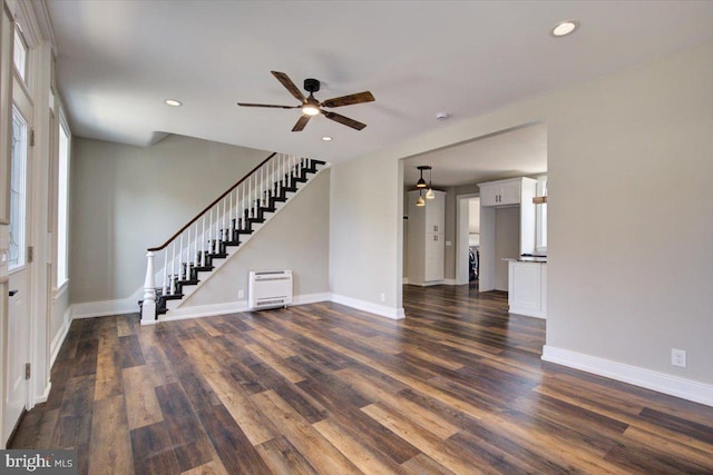 unfurnished living room with baseboards, stairs, a ceiling fan, and dark wood-style flooring