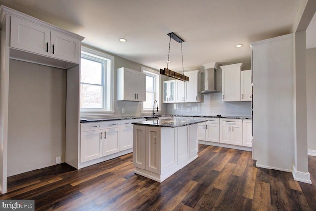 kitchen featuring dark wood finished floors, decorative backsplash, white cabinets, and wall chimney exhaust hood