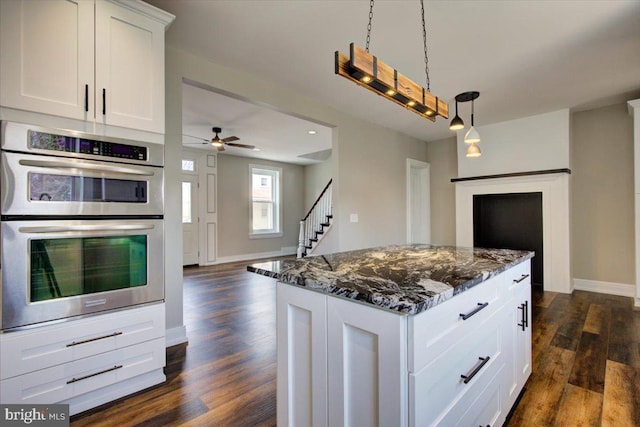 kitchen with a kitchen island, dark wood finished floors, dark stone counters, double oven, and white cabinets