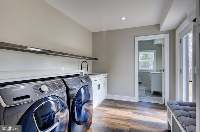 washroom with wood finished floors, baseboards, cabinet space, a sink, and independent washer and dryer