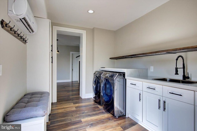 laundry area featuring an AC wall unit, light wood-style flooring, a sink, cabinet space, and separate washer and dryer