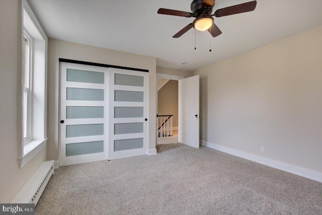 unfurnished bedroom with multiple windows, carpet, and baseboard heating