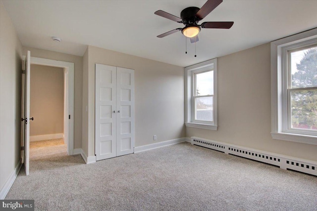 unfurnished bedroom featuring multiple windows, baseboards, a baseboard heating unit, and carpet