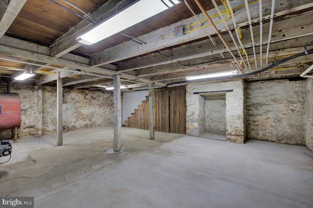 unfinished basement featuring heating fuel and stairway