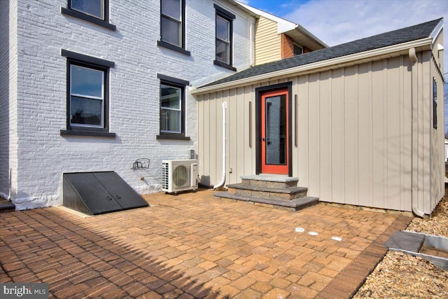 back of property with brick siding, board and batten siding, entry steps, ac unit, and a patio