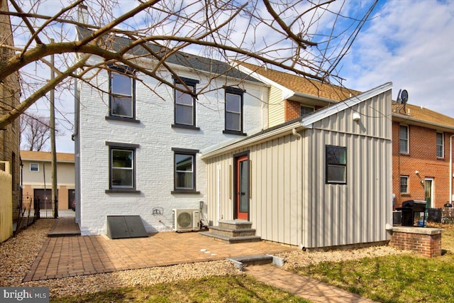 rear view of house with brick siding, fence, entry steps, ac unit, and a patio