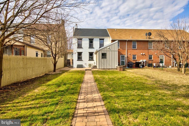 back of house featuring a lawn, board and batten siding, and fence