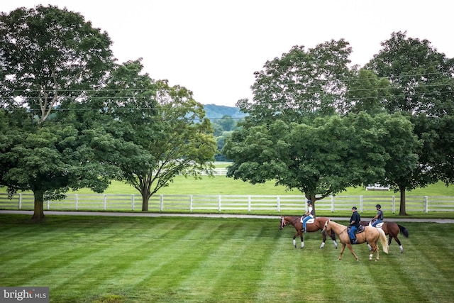 view of home's community featuring fence, a rural view, and a lawn