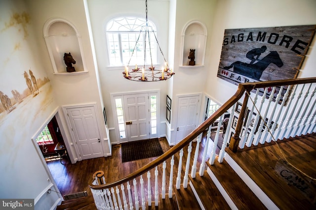 foyer entrance featuring stairway, wood finished floors, a wealth of natural light, and a chandelier