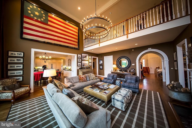 living room featuring wood finished floors, a high ceiling, recessed lighting, arched walkways, and a notable chandelier