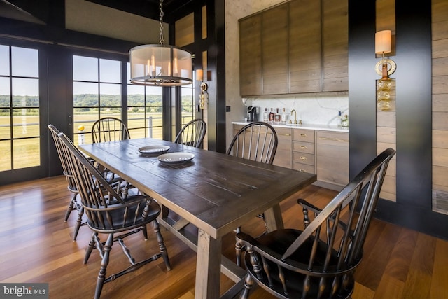 dining area with a chandelier, wet bar, and wood finished floors