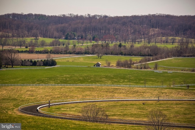 view of home's community with a yard, a rural view, and a view of trees