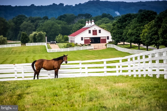 view of stable with a rural view and a forest view