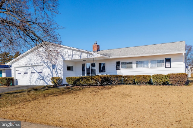 single story home with driveway, a chimney, a garage, and a front yard