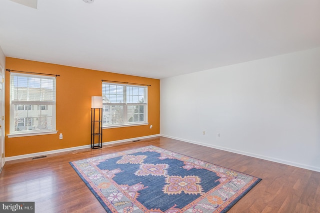 unfurnished room featuring visible vents, baseboards, and wood finished floors