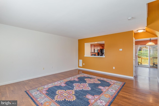 spare room with baseboards and wood finished floors