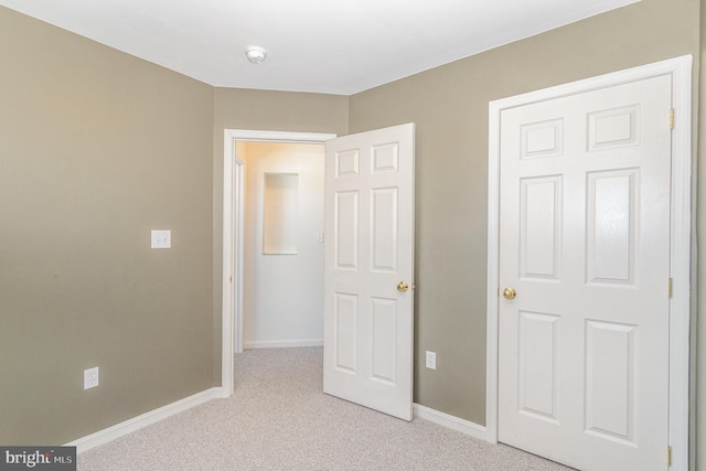 unfurnished bedroom featuring baseboards and light carpet