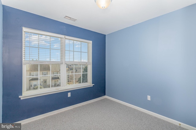 empty room featuring carpet flooring, baseboards, and visible vents