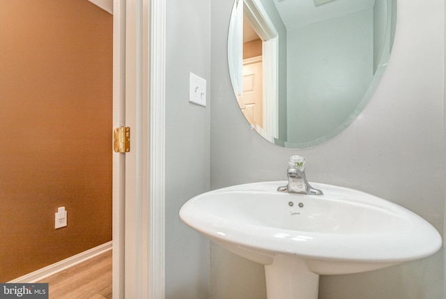 bathroom featuring wood finished floors, baseboards, and a sink