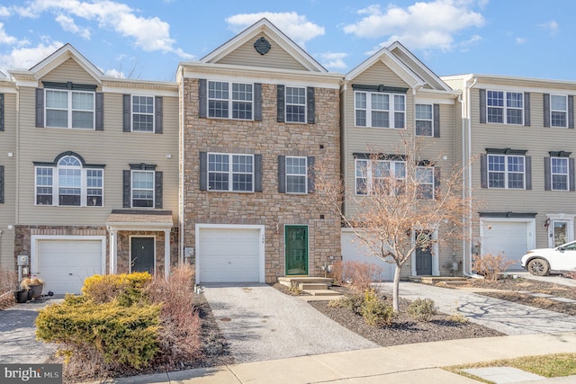 townhome / multi-family property featuring stone siding, driveway, and an attached garage