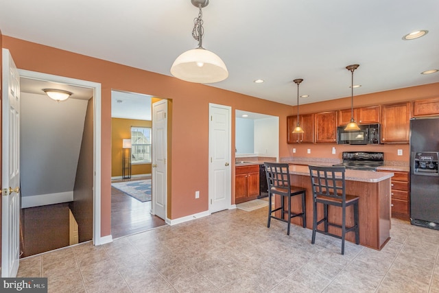 kitchen featuring black appliances, light countertops, brown cabinets, and a center island