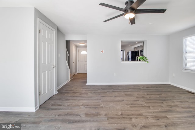 unfurnished living room with a ceiling fan, baseboards, and wood finished floors