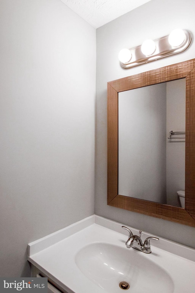 bathroom featuring toilet, a textured ceiling, and vanity