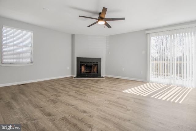 unfurnished living room with wood finished floors, a fireplace, visible vents, and baseboards