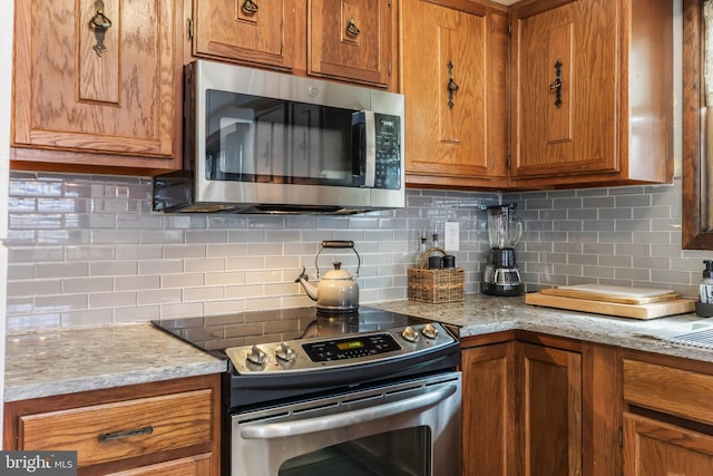 kitchen featuring decorative backsplash, brown cabinets, and appliances with stainless steel finishes